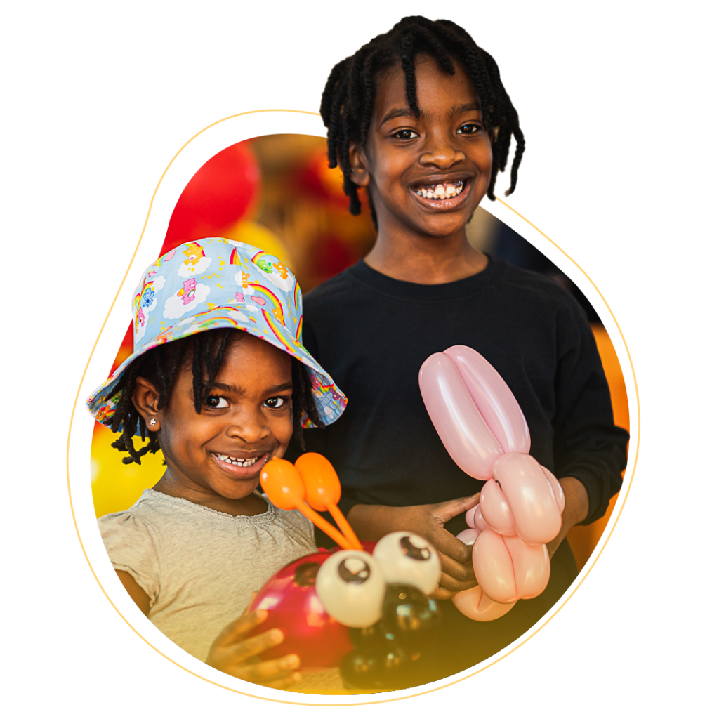 Two smiling grade school kids holding balloon animals